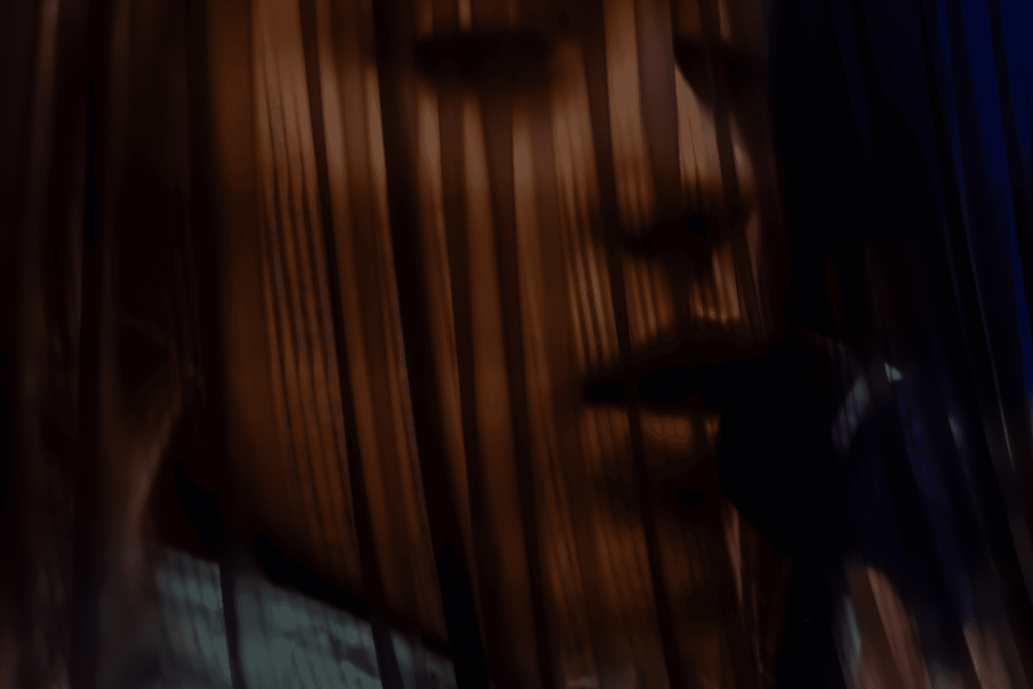 Close-up of a performer's face lit through vertical light slats