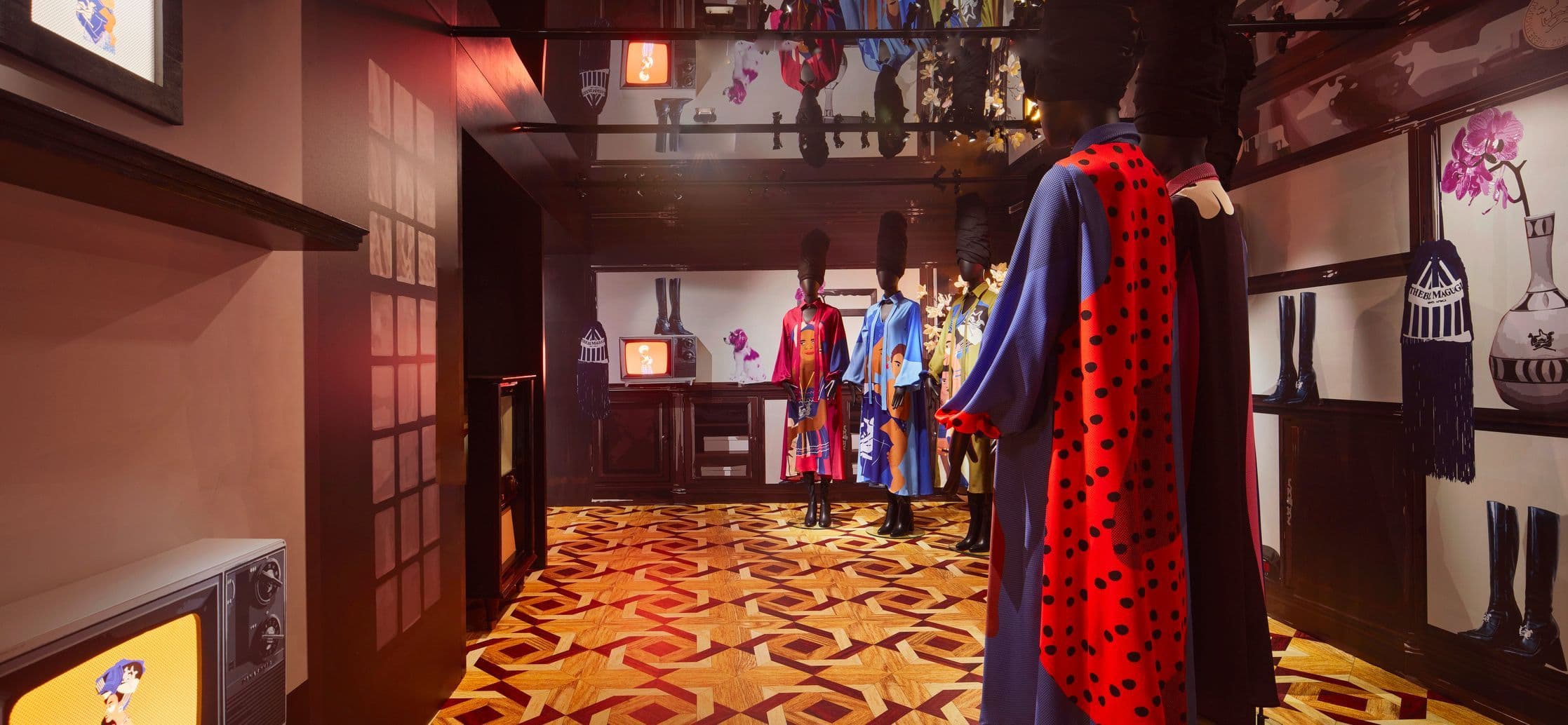 Gallery hallway with a red-lined black robe on a mannequin in the foreground and framed art along the corridor.