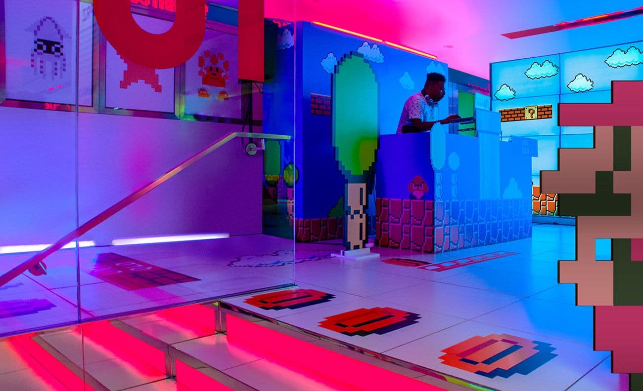 Mirrored gallery hallway with a pixel-art Super Mario mural and neon lighting, an oversized orange question-mark block on the floor.