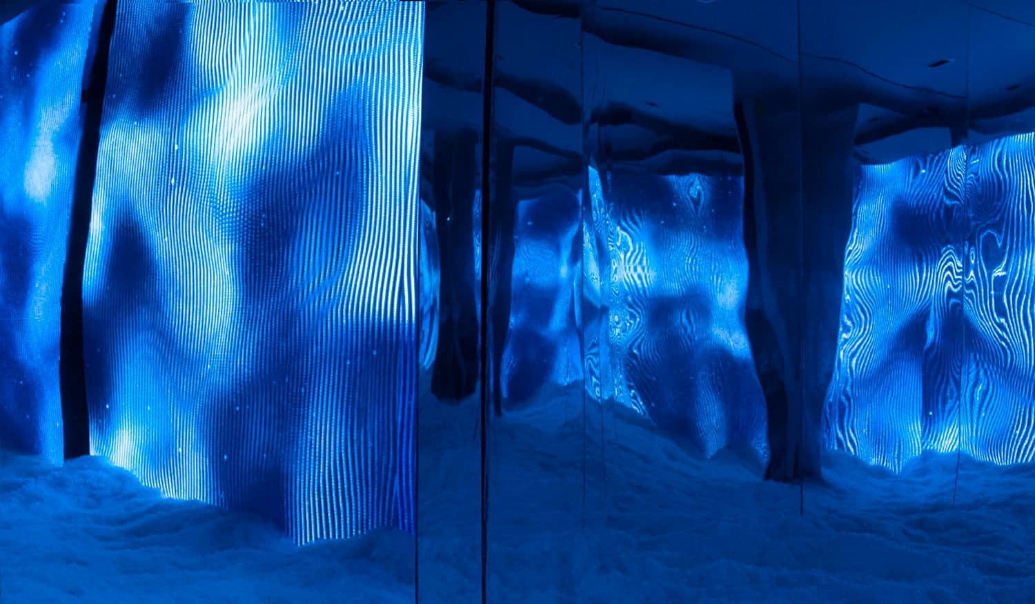 Rippling blue light projected across mirrored panel walls, creating a wave-like pattern.