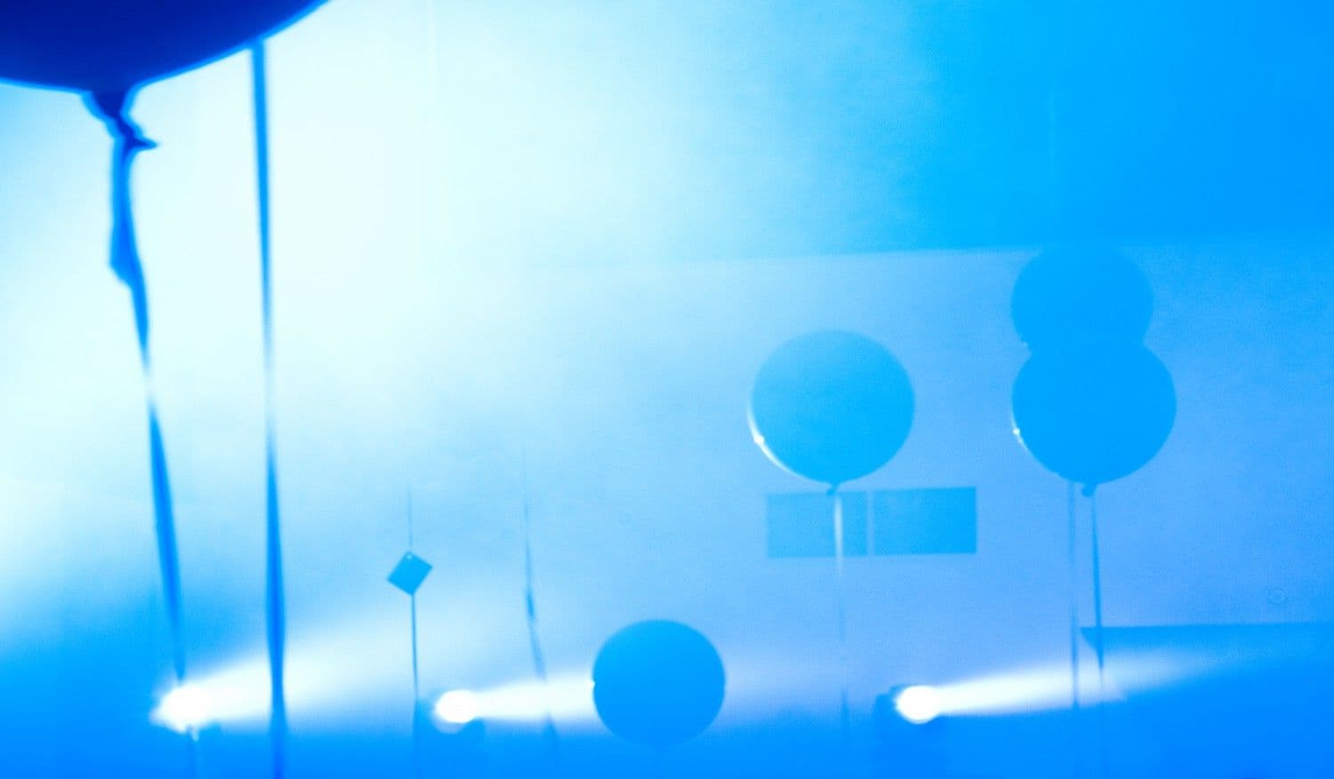 Blue room with light beams, hanging round lanterns, and squiggly decorative shapes.