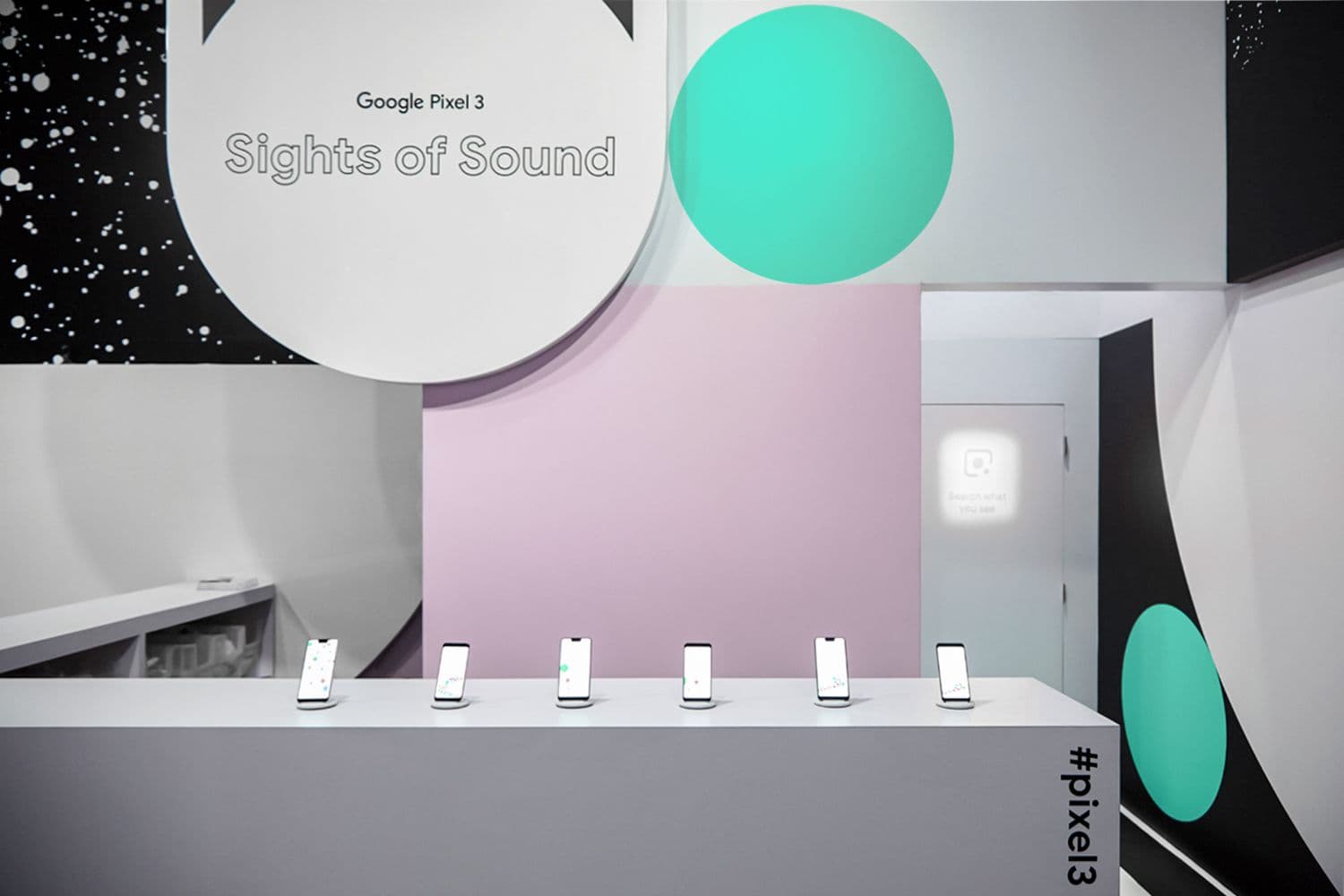 Google Pixel 3 "Sights of Sound" exhibit with a black and white sunburst pattern and teal phones displayed on a shelf.