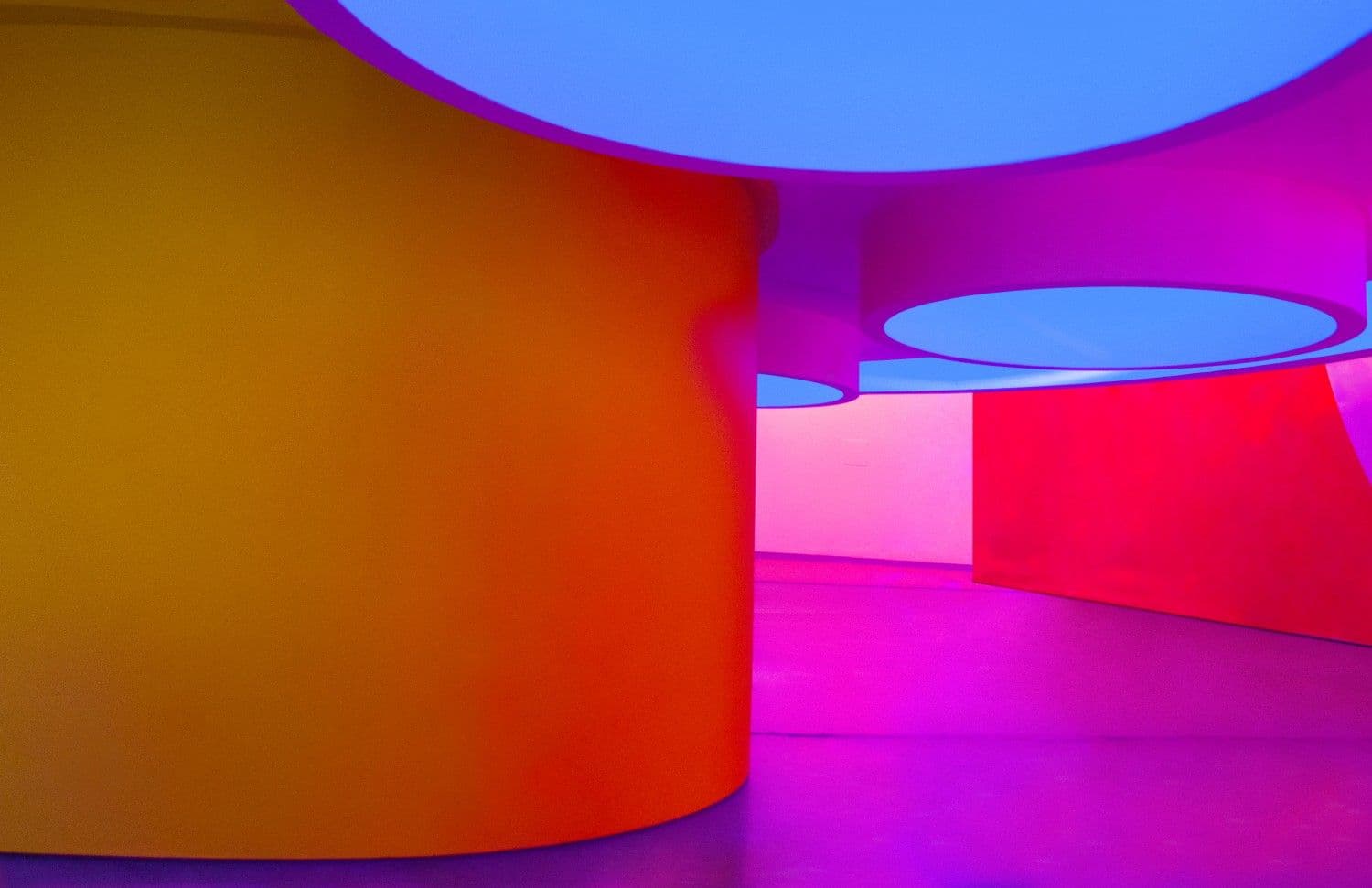 Orange and pink round pedestal tables beneath blue circular ceiling discs.