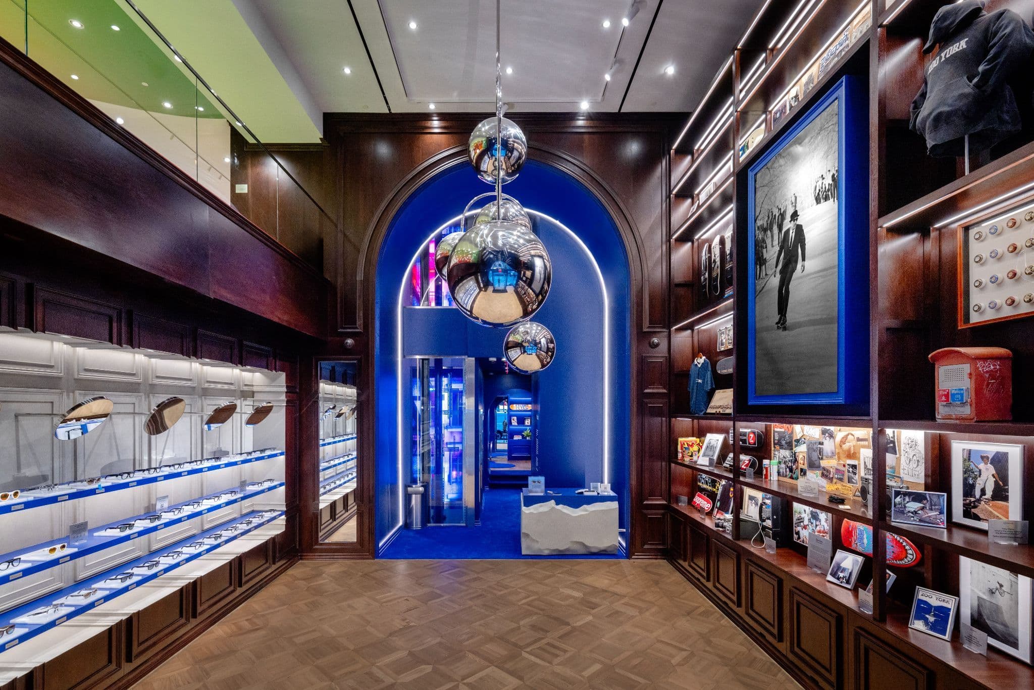 Store interior with a blue arched alcove holding mirrored ball fixtures, flanked by dark wood display cabinets and a rug printed with an illustrated scene.