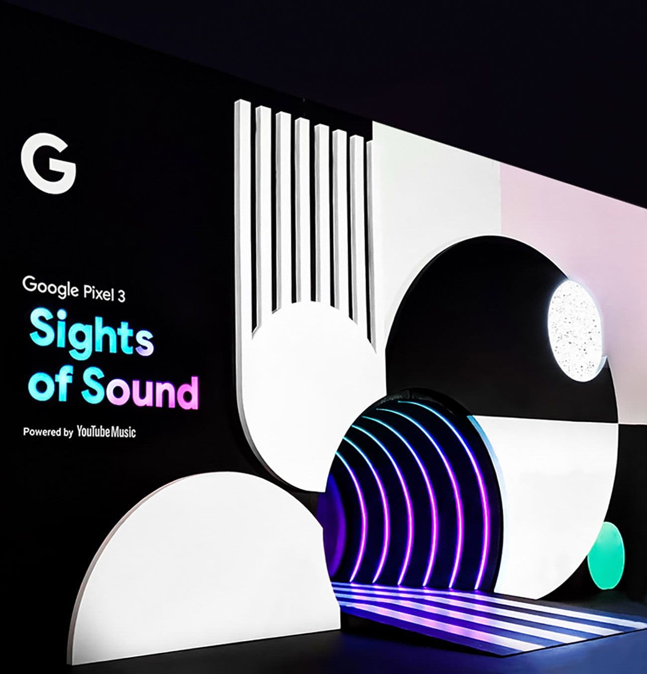 Illuminated Google Pixel 3 "Sights of Sound" sign with a black and white radial design and purple floor lighting.