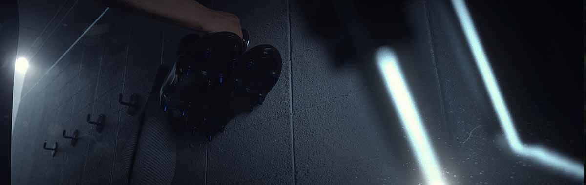 Close-up of a dark textured rock-like object on the floor beside a shoe and a light beam