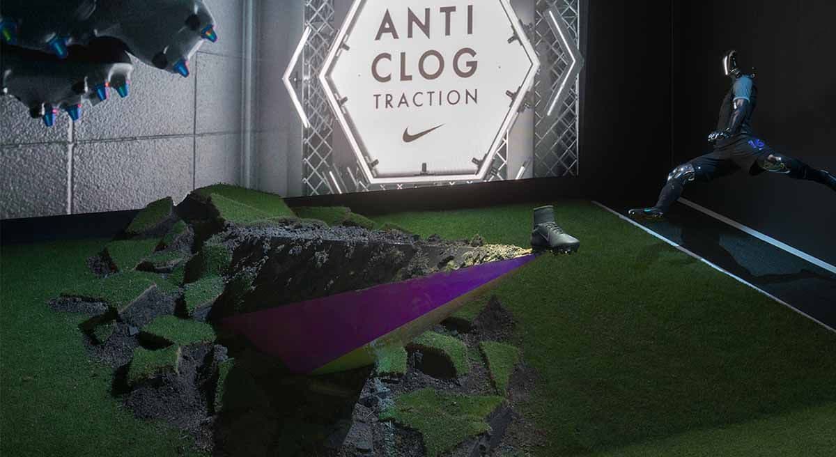 Floor installation of cracked rock-like debris and a purple cutout shape, with "Nike Anti-Clog Traction" projected on the wall behind and a runner silhouette in the background