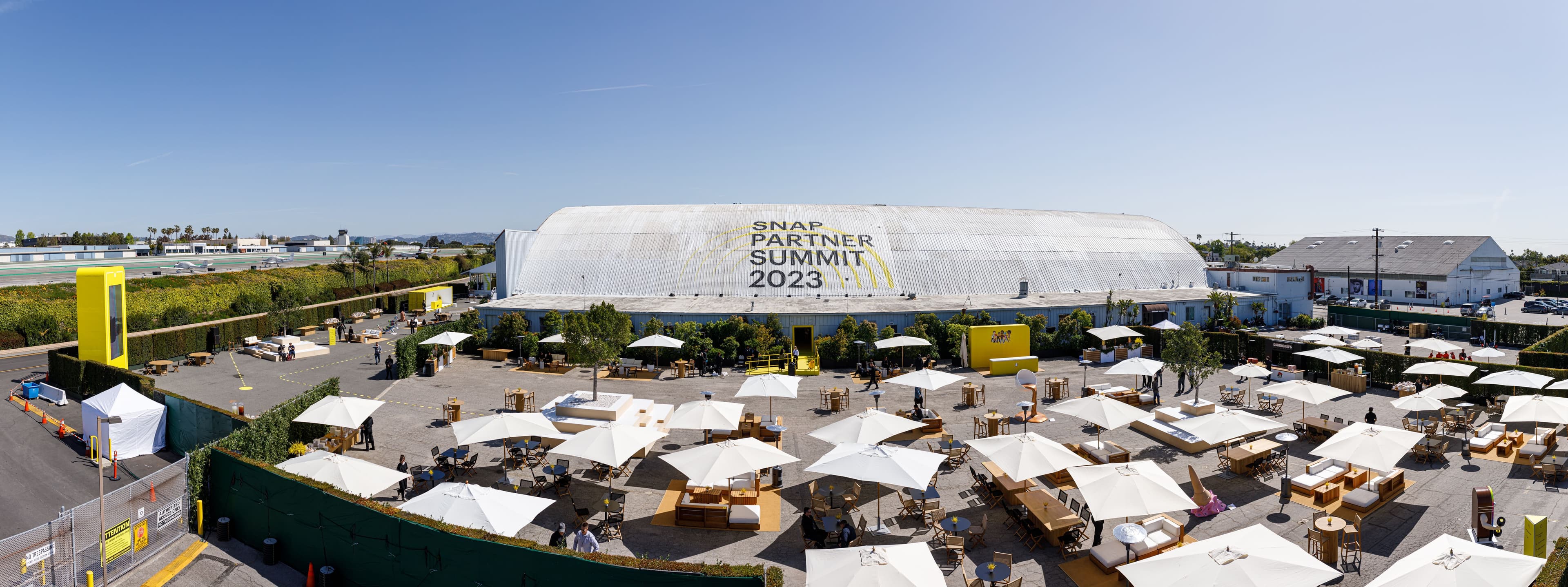 Aerial view of the event tent and surrounding parking lot filled with cars.
