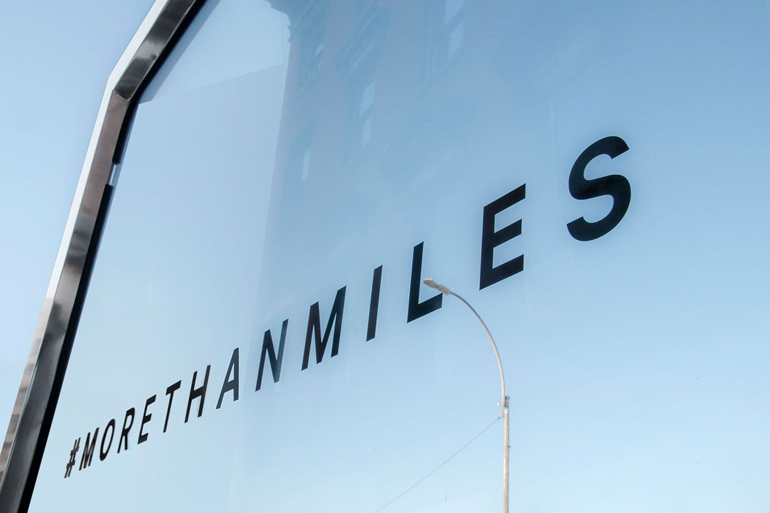 '#MORETHANMILES' text decal on the truck's glass panel with sky reflected in the surface