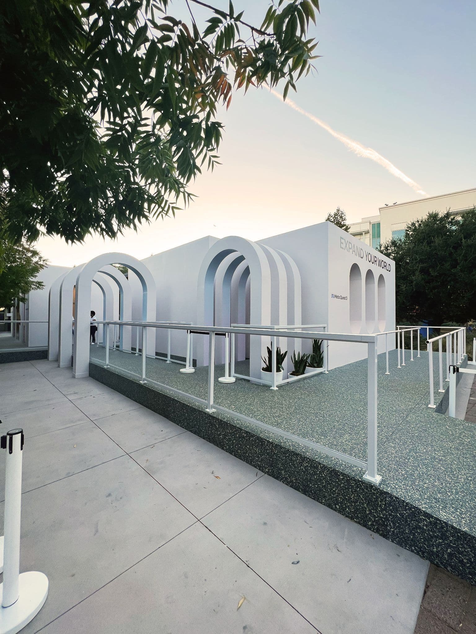 Wide view of the white arched Meta Connect pavilion at dusk with a walking path.