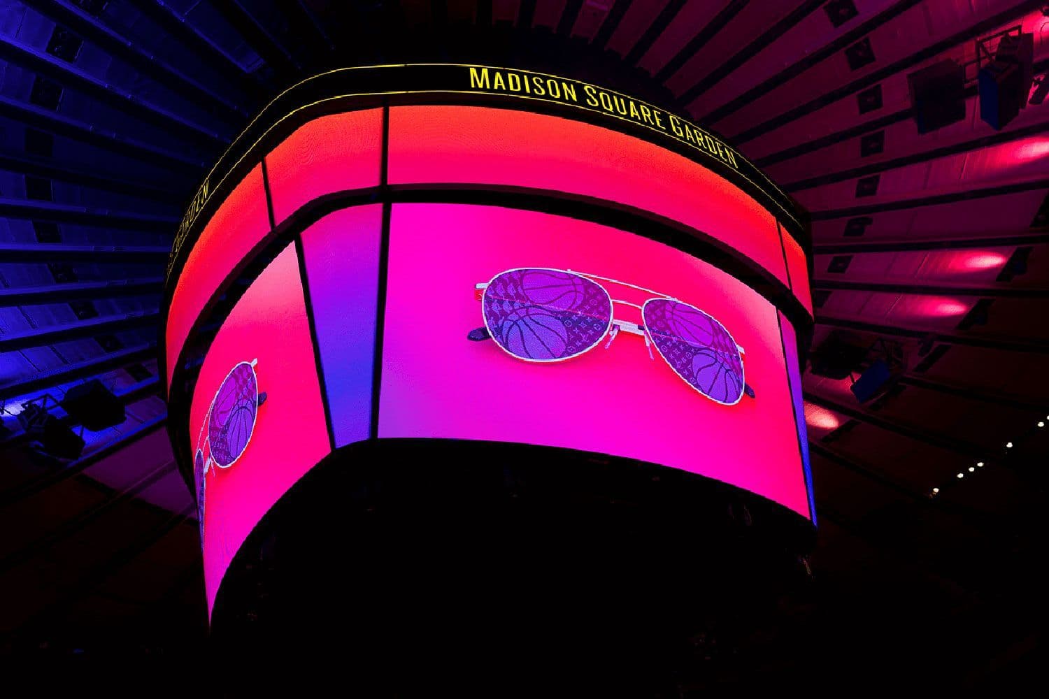 Curved LED display reading Madison Square Garden above a sunglasses graphic, lit in pink and purple.