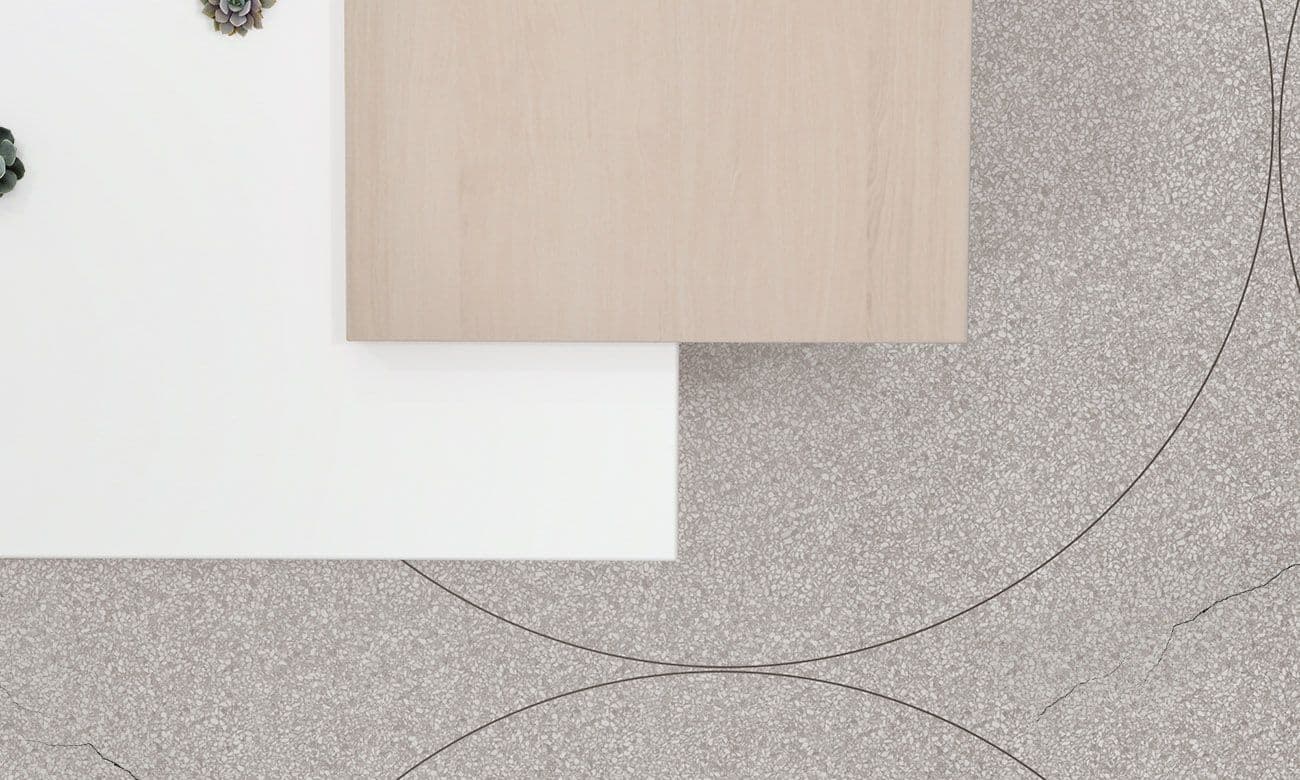 Overhead view of wooden and white cube-shaped stands on a speckled terrazzo floor with cracked linear patterns