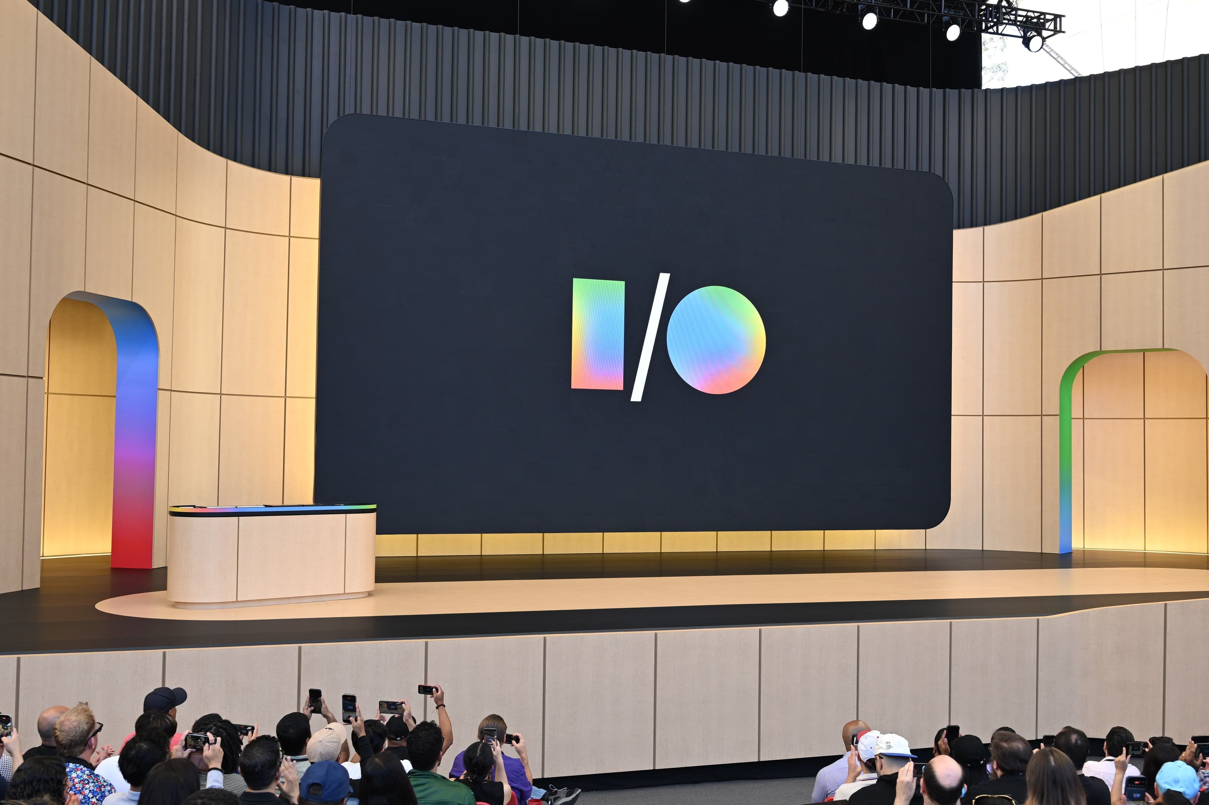 Empty keynote stage with a large screen displaying the I/O logo, framed by wooden arches and a colorful block backdrop.