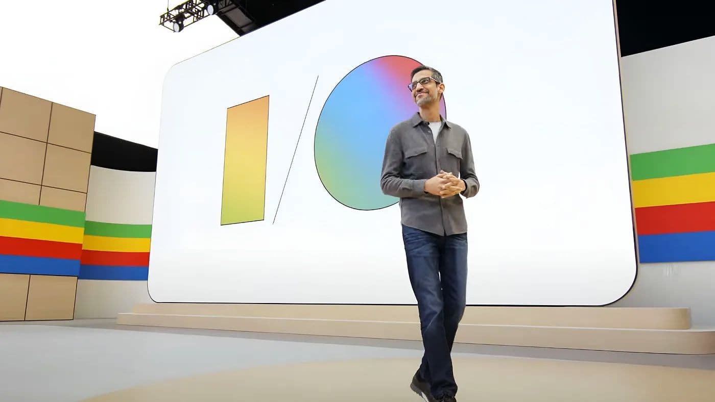 Presenter walking on stage in front of a screen showing the multicolor I/O logo.