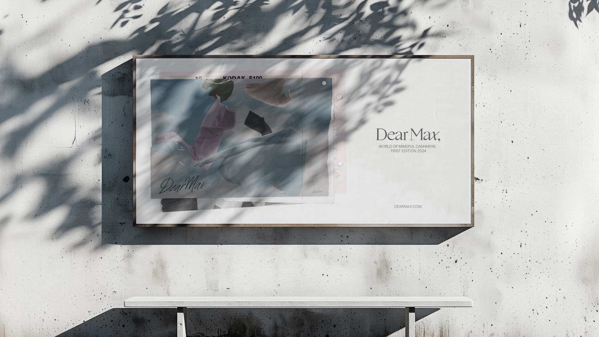Framed Dear Max campaign poster mounted on a textured wall above a plain white bench.