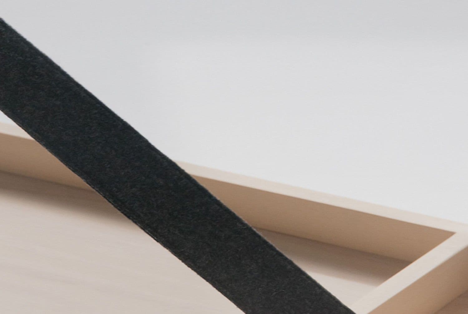 Close-up of a pale wood tray corner with the COS logo engraved on its side.