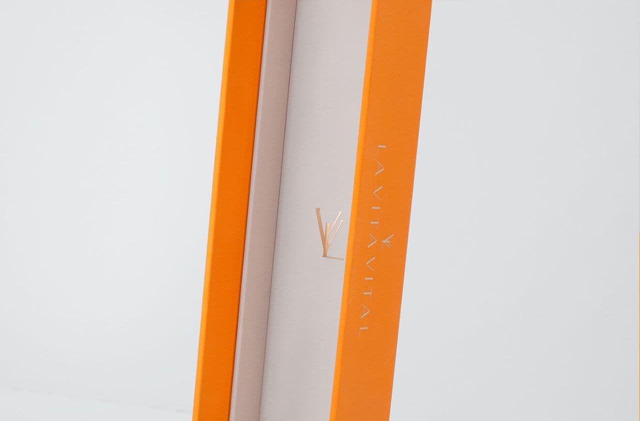 Close-up of the spine of an orange book-style case with a gold foil logo, standing upright against a white background.