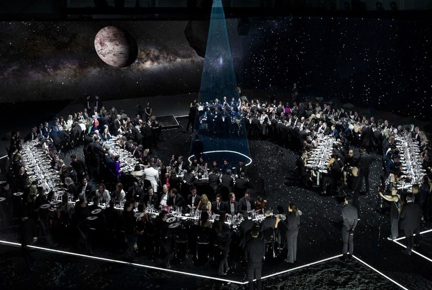 Elevated view of the same hexagonal banquet setup with a red planet and blue spotlight beam shining over the center table.