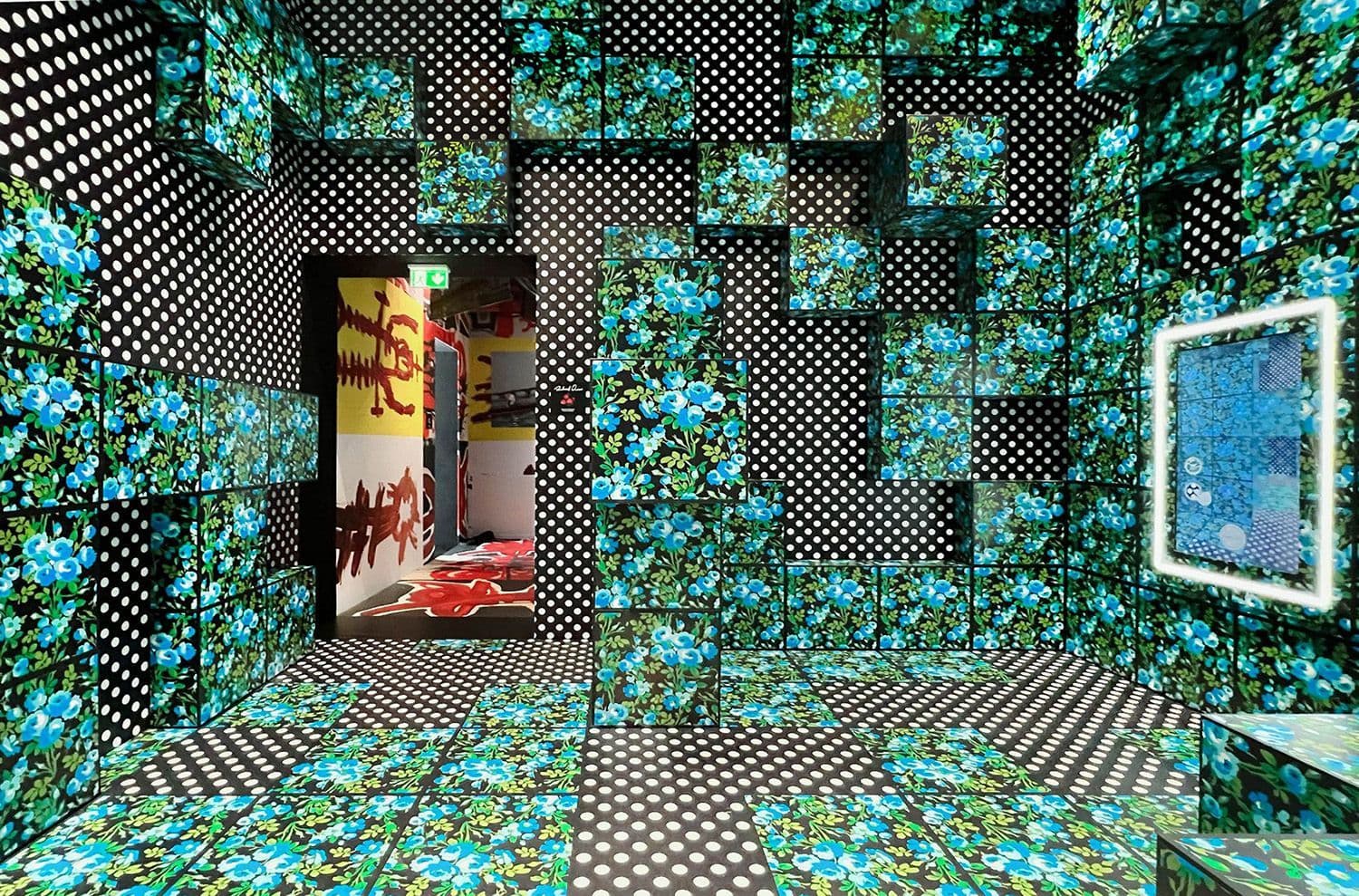 Teal floral patterned room with a doorway revealing a red garment display and a mirrored panel on the right wall.