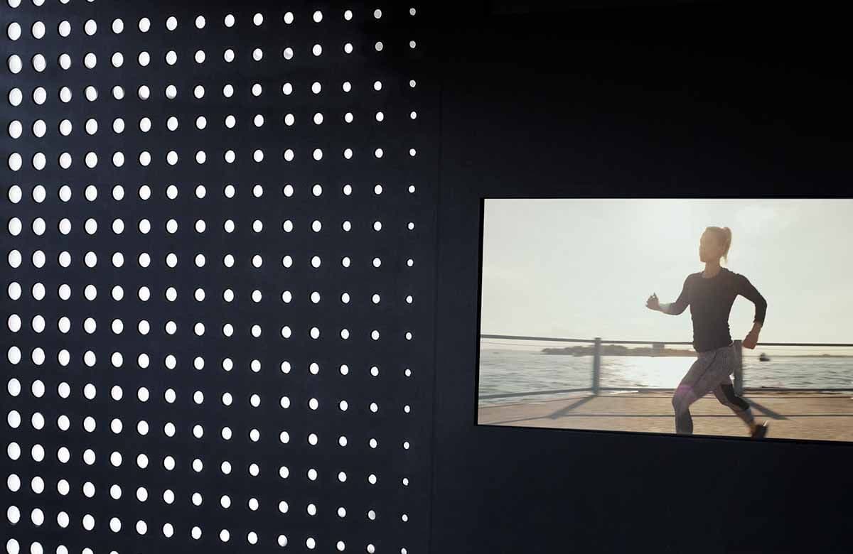Perforated dot-pattern wall panel beside a screen showing a runner on a beach path