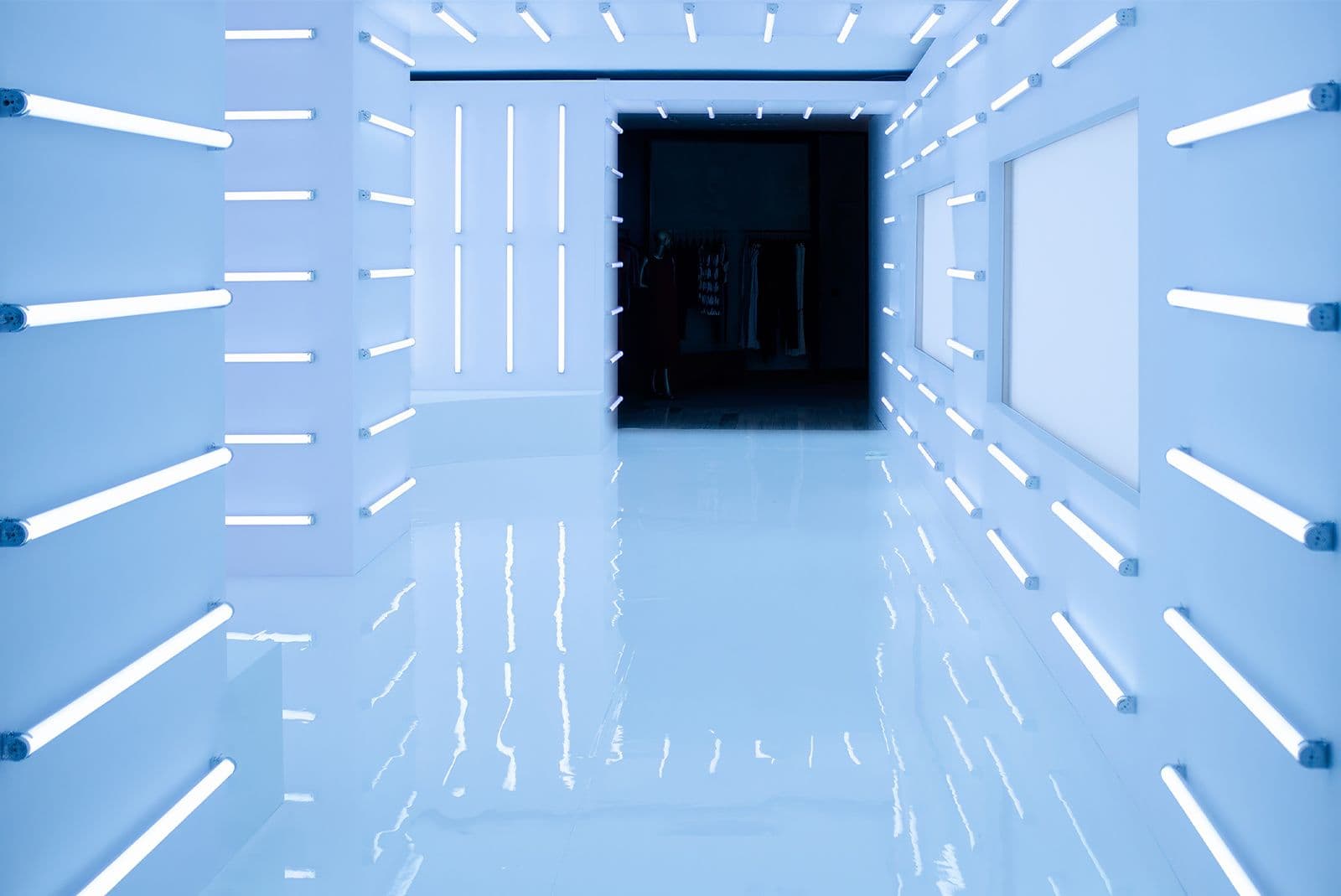 Cool white and blue neon corridor lined with horizontal light bars, dark doorway at the end, glossy everything.