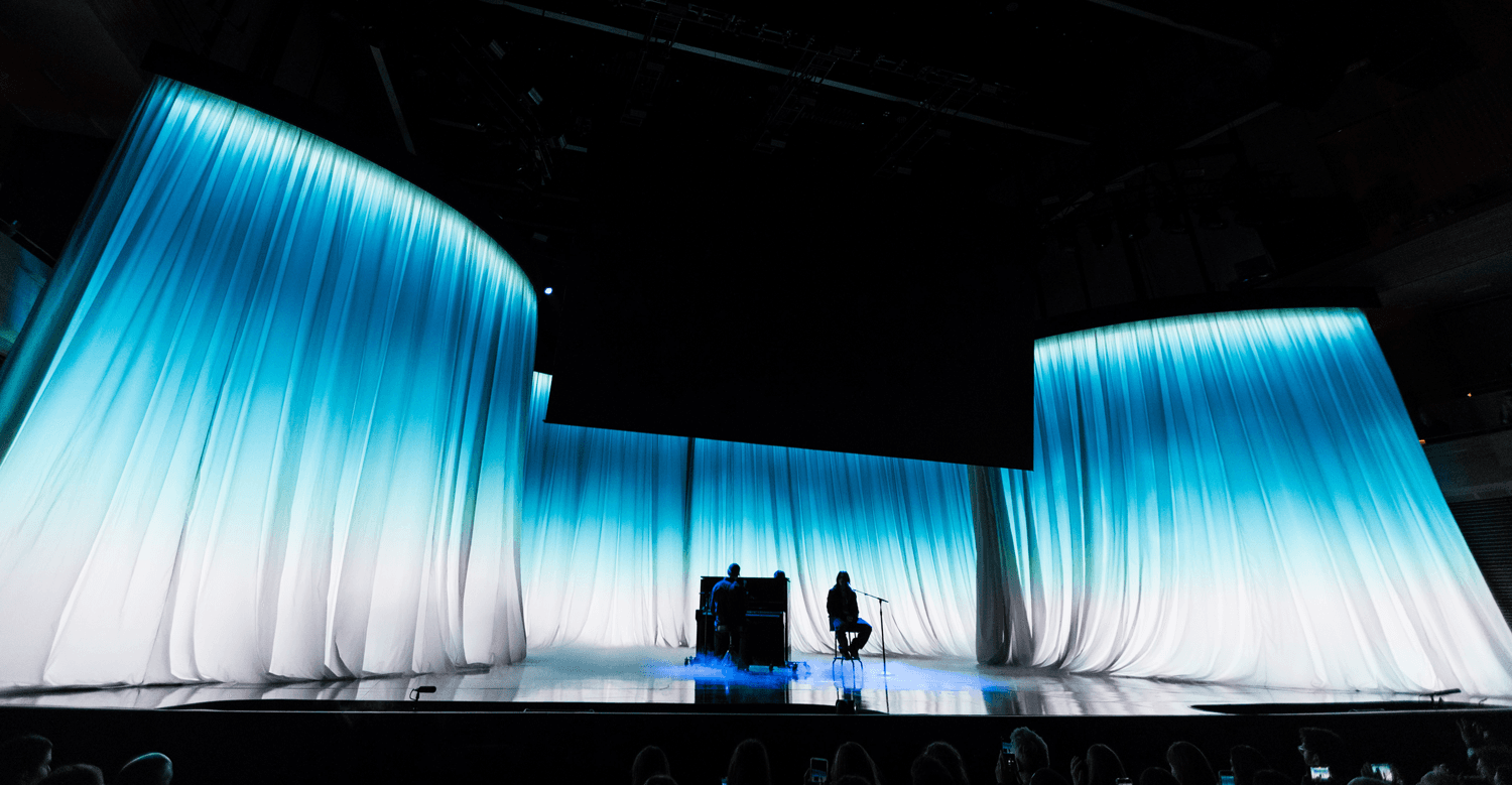 Wide shot of a stage flanked by tall white curtain-like light panels