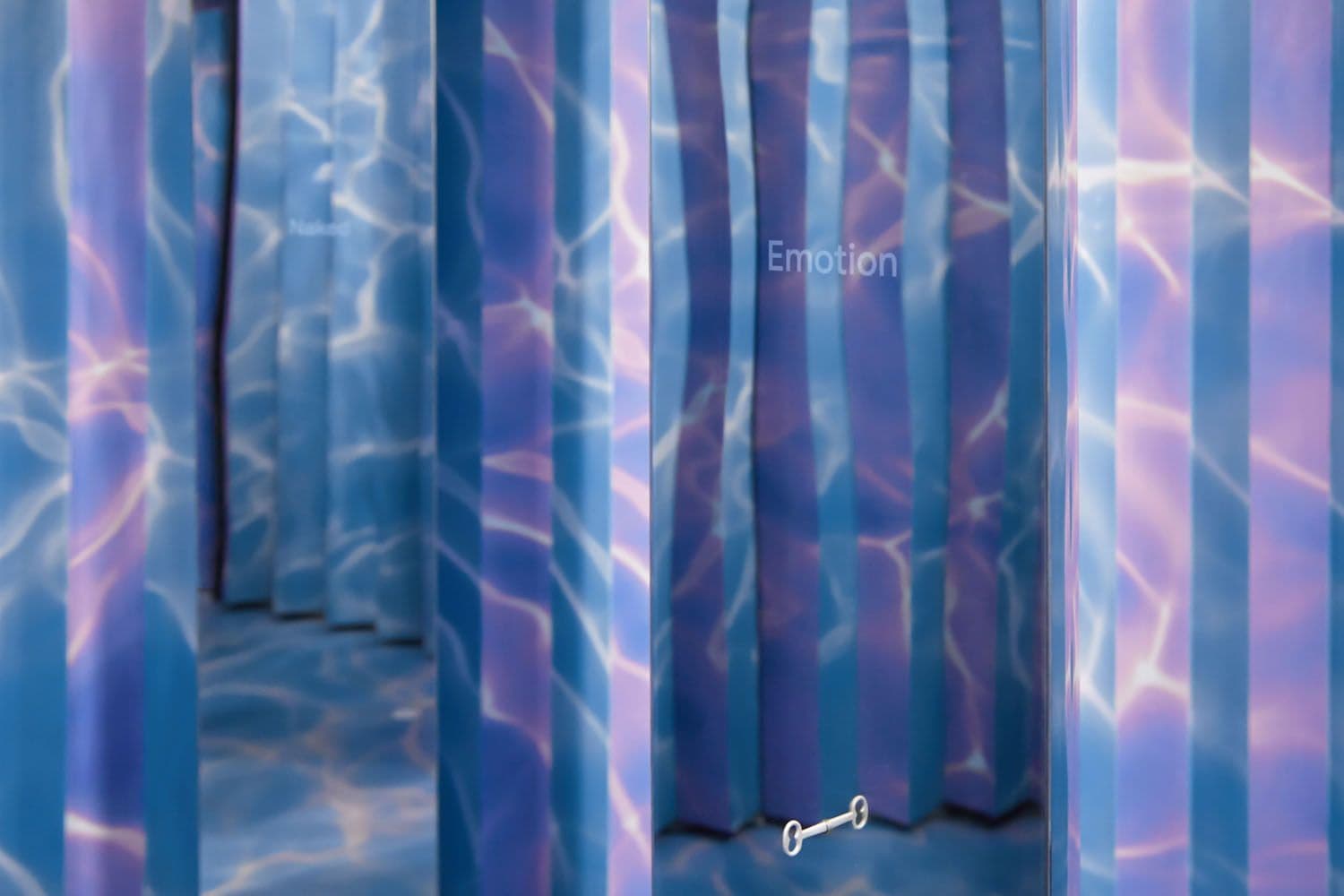 Blue-lit room with rippling light patterns across vertical panels.