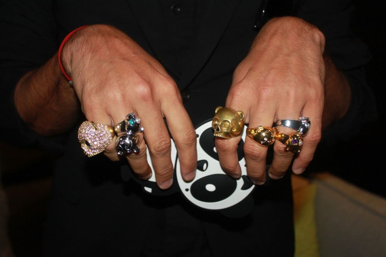 Close-up of two hands wearing multiple statement rings, including a black-and-white panda-face ring.