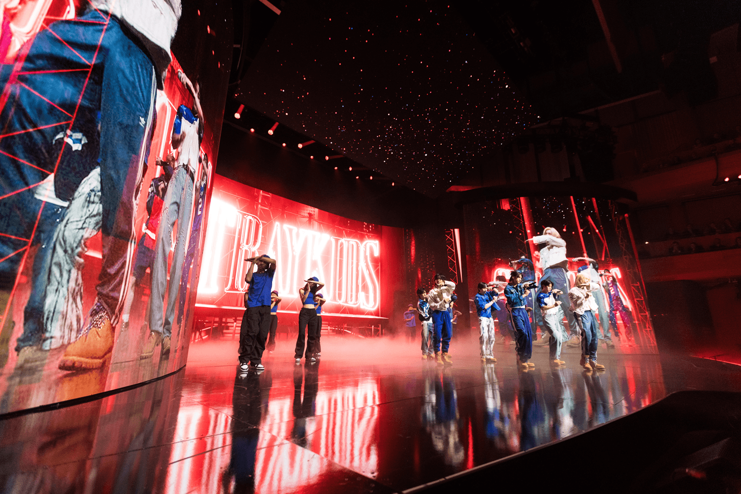Dancers performing in front of red stage screens showing photo collages