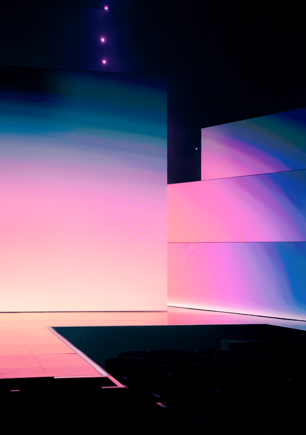 Vertical stage screen displaying a pink, teal, and blue geometric gradient pattern