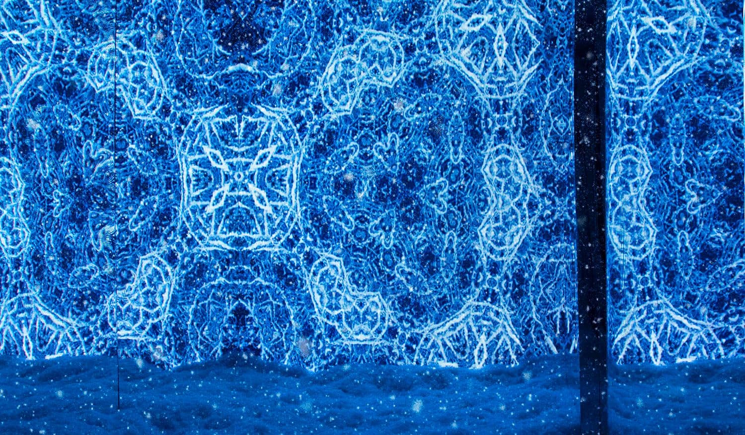 Kaleidoscopic blue LED light pattern reflected across mirrored panels, resembling frost or ice crystals.