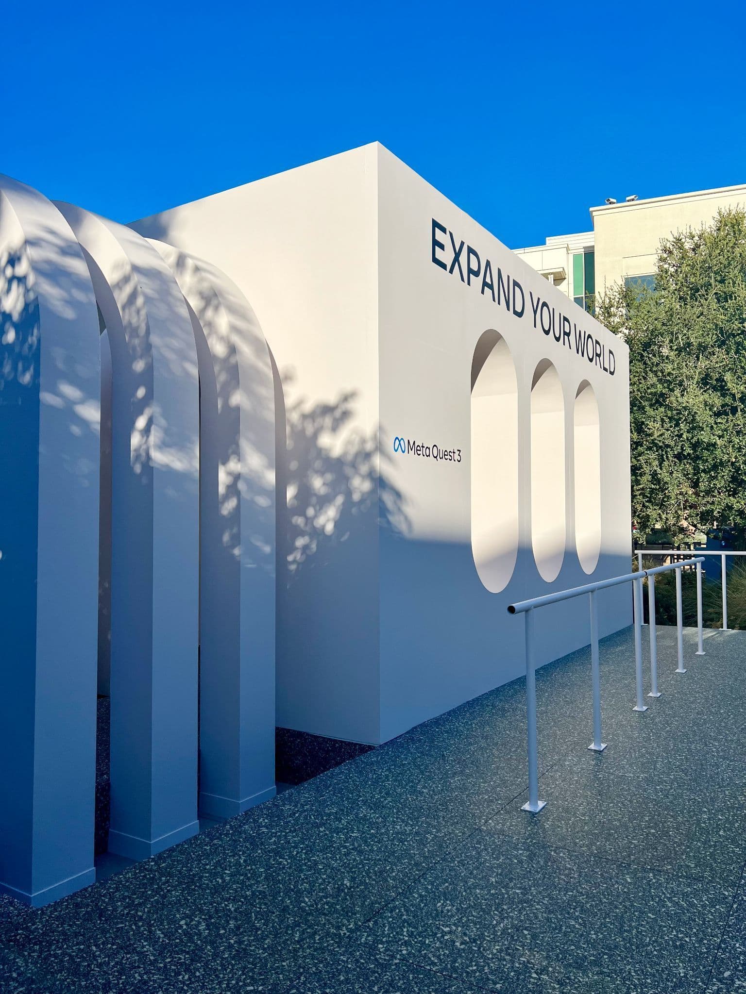 White arched pavilion exterior with 'Expand Your World' signage for Meta Quest 3.