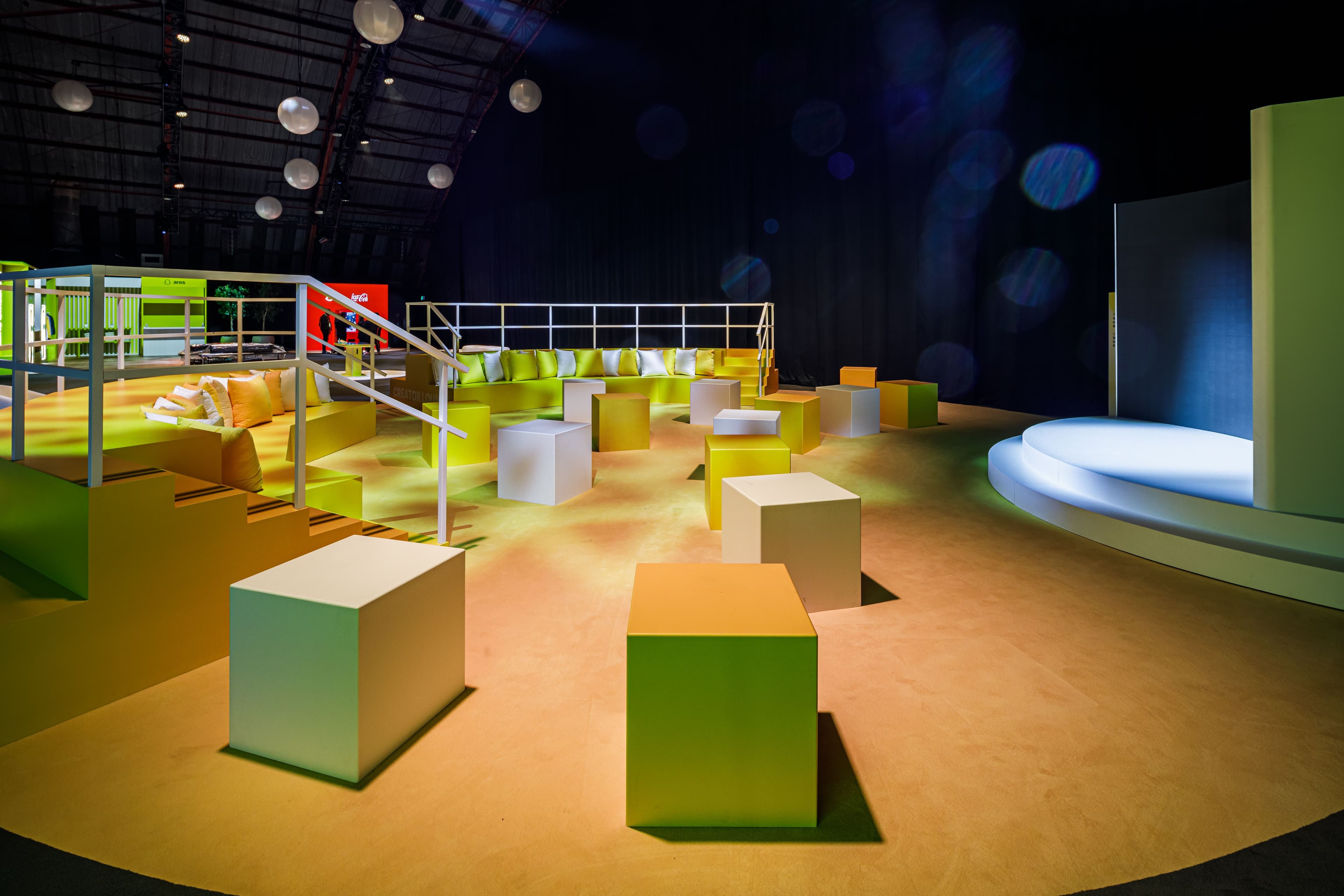 Dim indoor lounge space with modular seating blocks and ambient lighting.