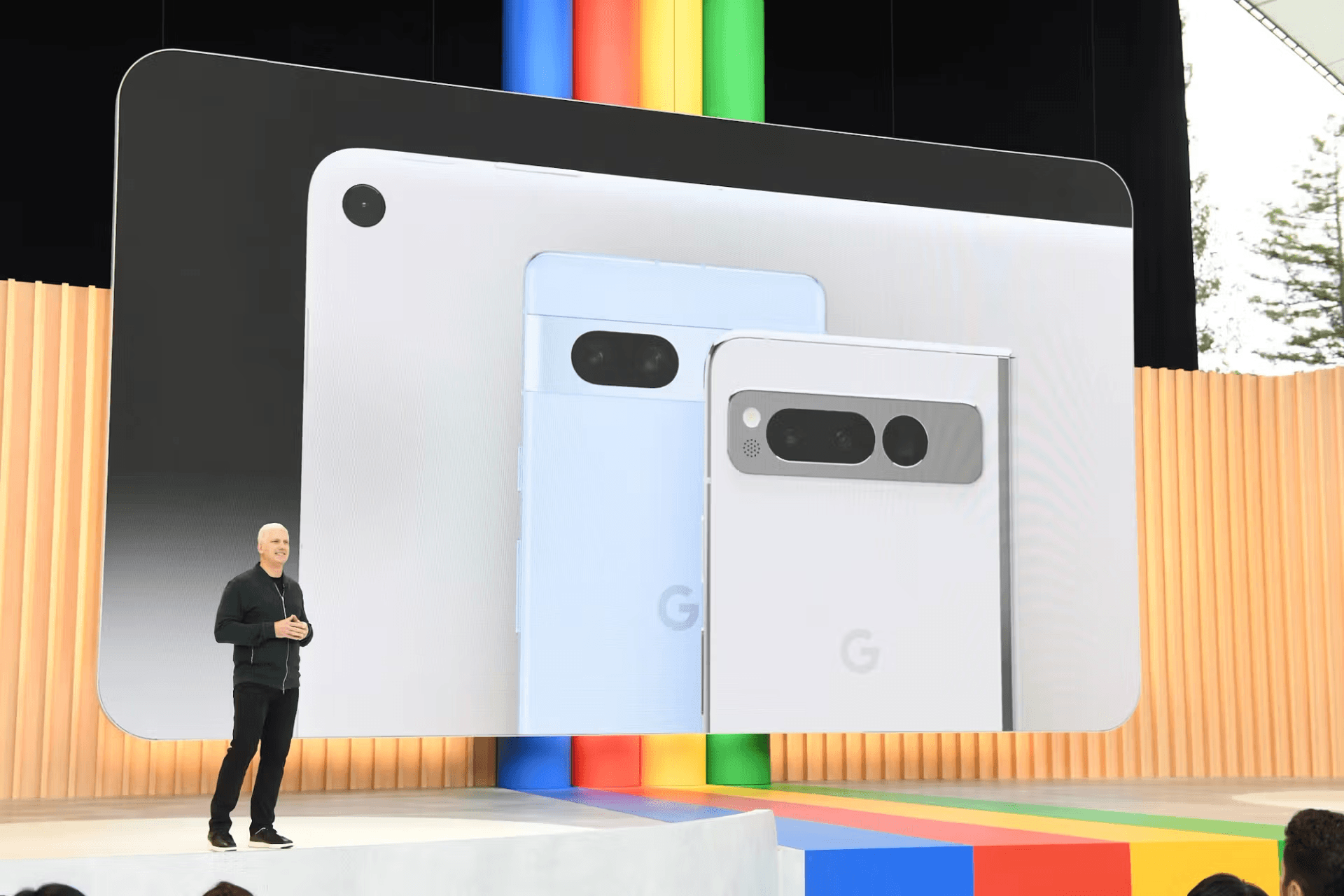 Presenter standing beside three Pixel models displayed on stage, colorful backdrop behind.
