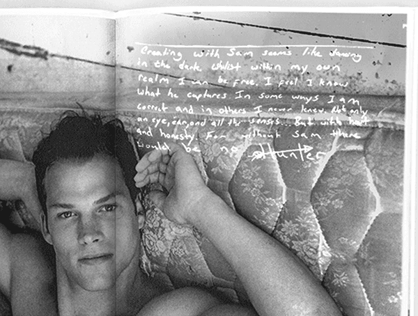 Book spread showing a shirtless man lying on a bed beside a page of handwritten text.