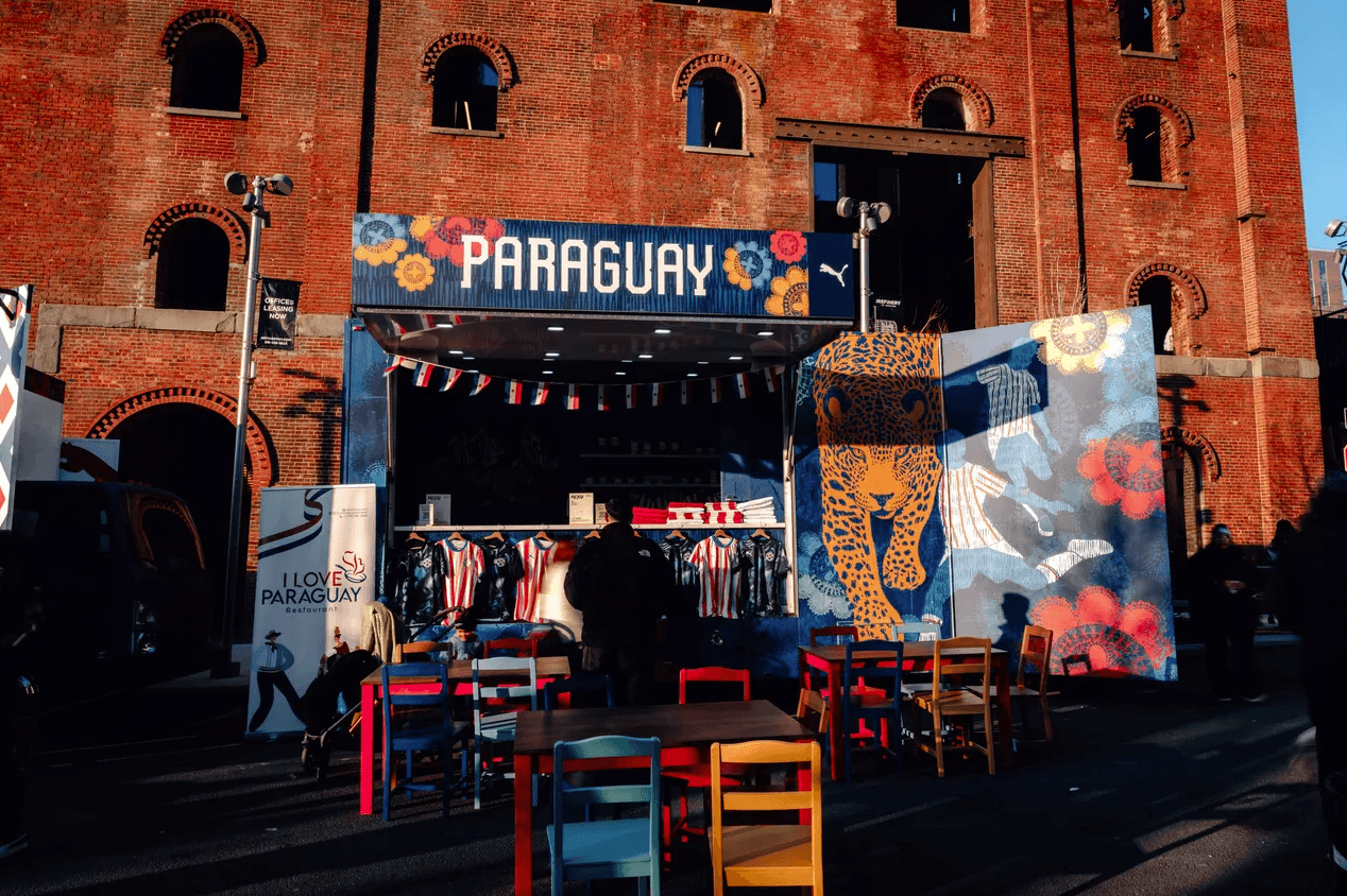 Historic red-brick warehouse building with a 'PARAGUAY' branded activation and colorful mural installed at its entrance.