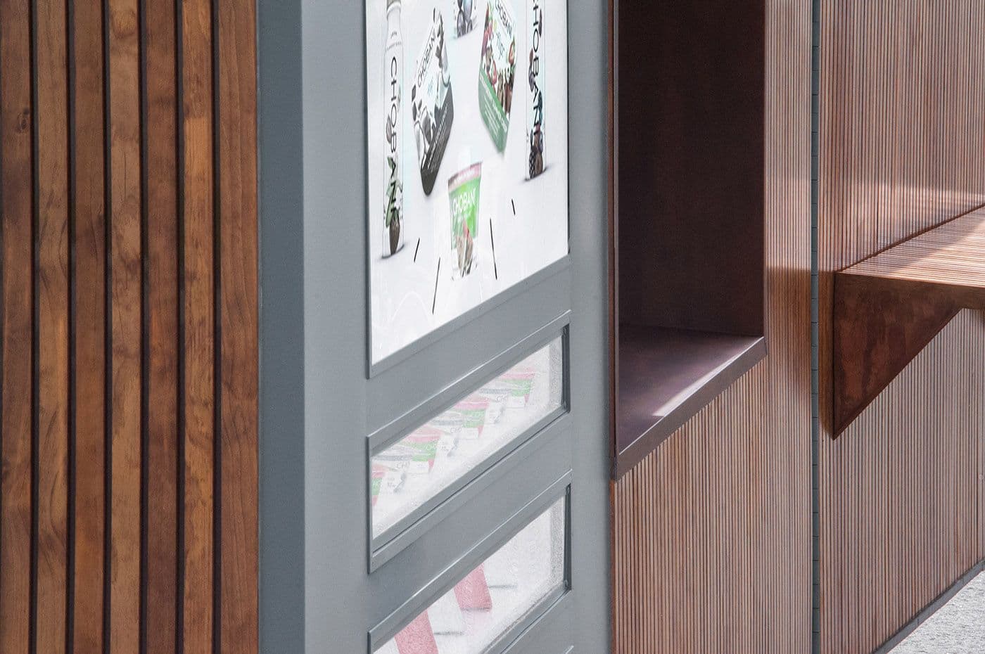 Close-up of wood-slat paneling with a wall-mounted screen and a small wooden shelf.