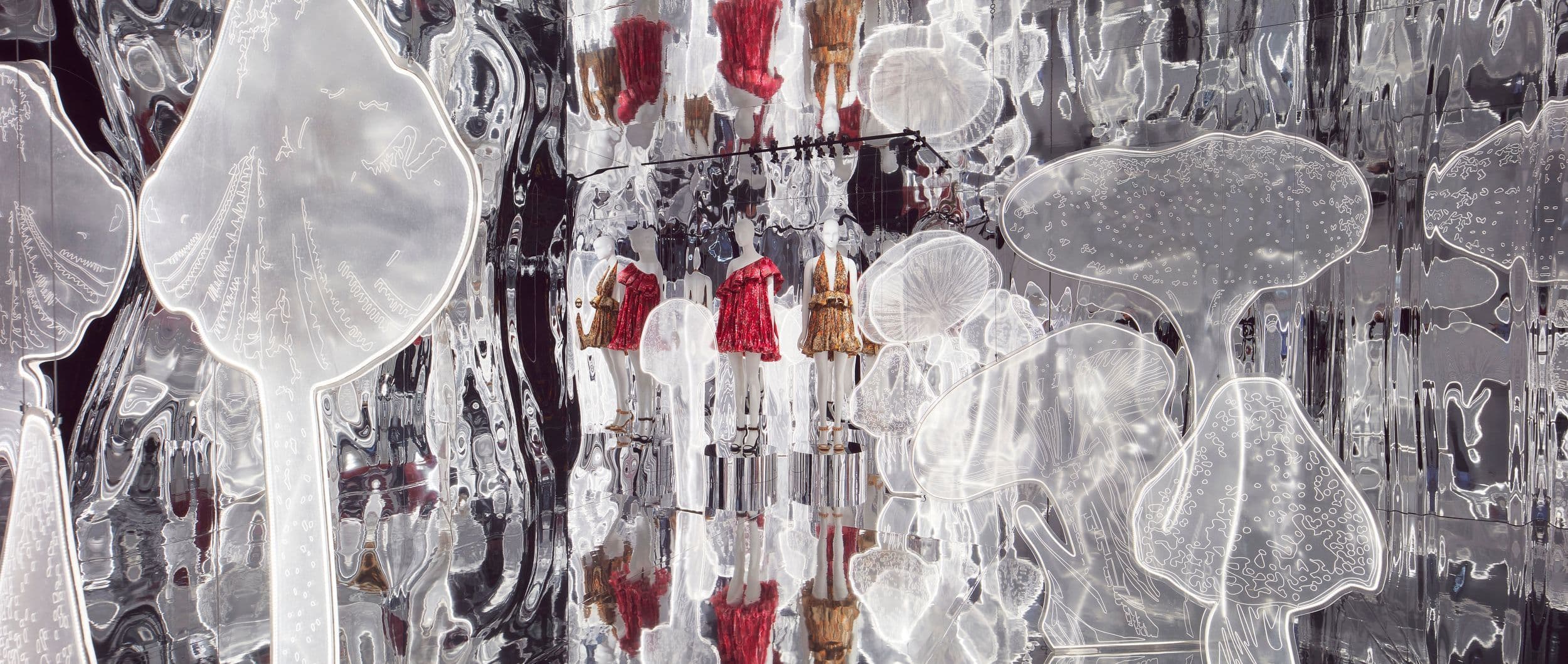 Mirrored installation with translucent inflated forms and hanging red garment pieces.