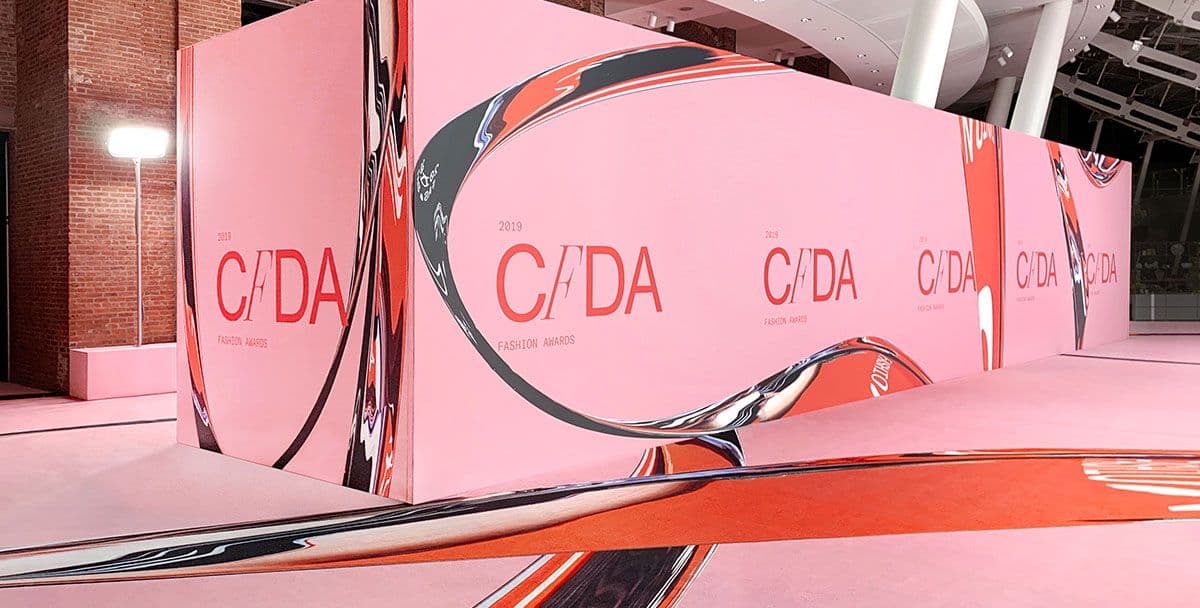 Pink event stage with C/DA branded panels and a glossy black curved reflective floor