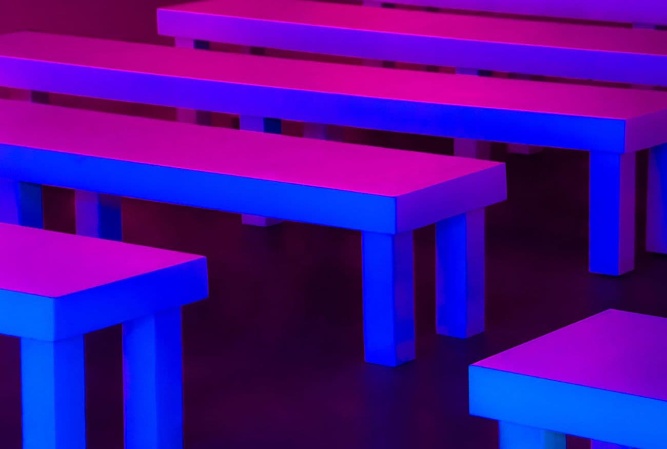 Rows of bench seating lit in pink and blue neon light.