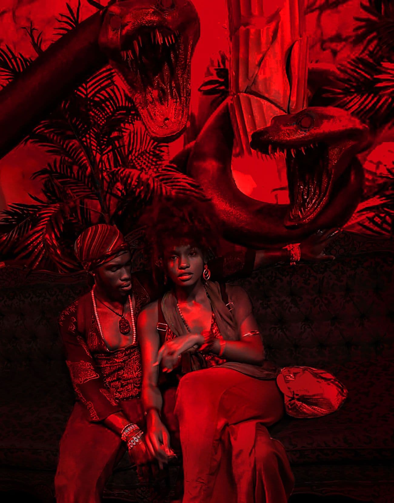 Two people sitting amid a red-lit jungle installation with dinosaur silhouettes and palm fronds.