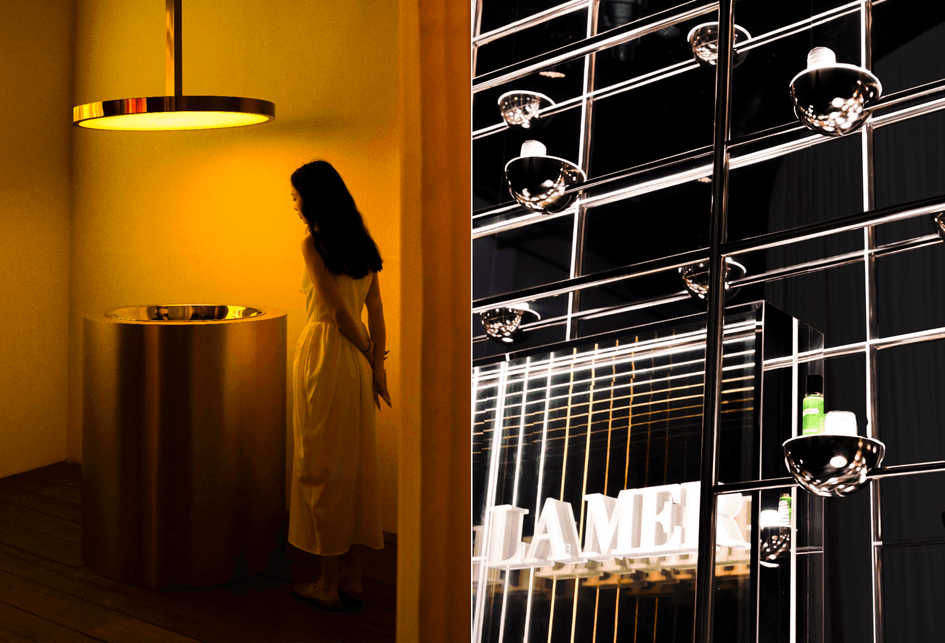 Dimly lit room with a woman standing near an amber pendant light beside a metal display of hanging bottles and a La Mer sign.