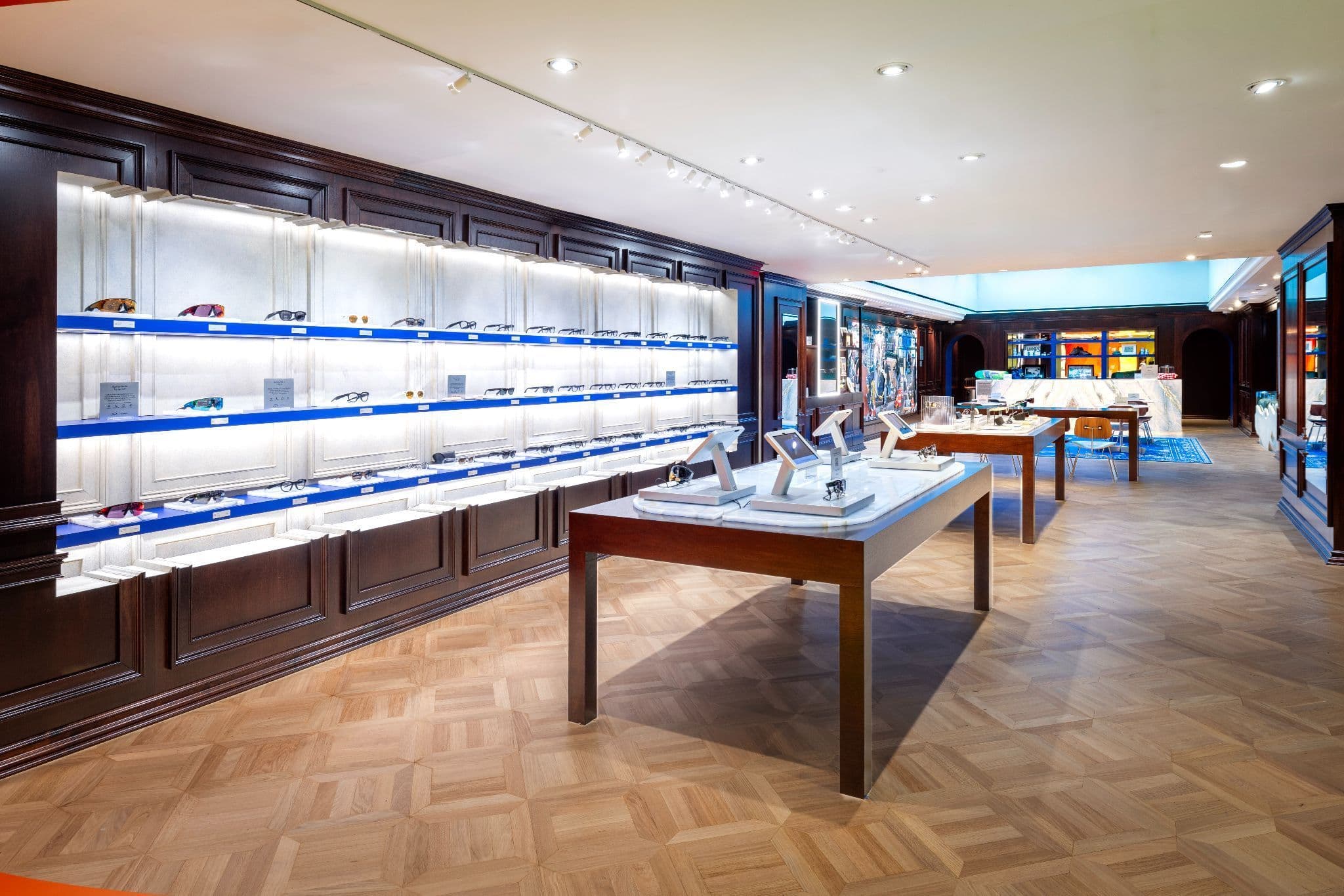 Dark wood-paneled sales floor with backlit shelving and freestanding display tables on parquet flooring.